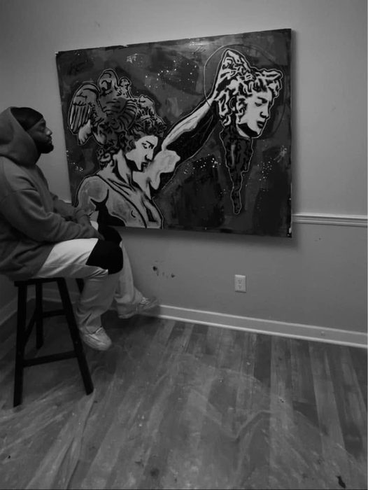 Black and white photo of Willie Austin seated on a stool, looking up at the painting on the wall