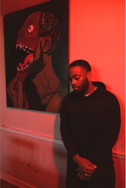 Willie Austin standing in red light beside the painting