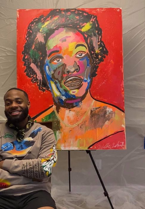 Willie Austin smiling beside his colorful portrait of his mother on a red background