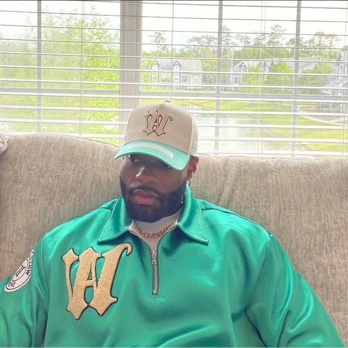 Willie Austin seated in the teal Willie Austin quarter zip and a cream W cap