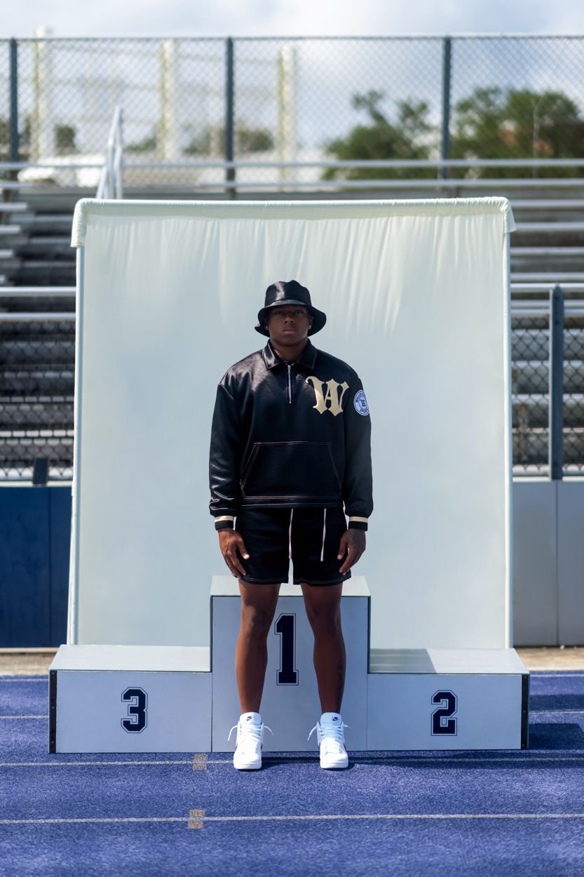 A model in a black Willie Austin hoodie standing on a first place podium in a stadium