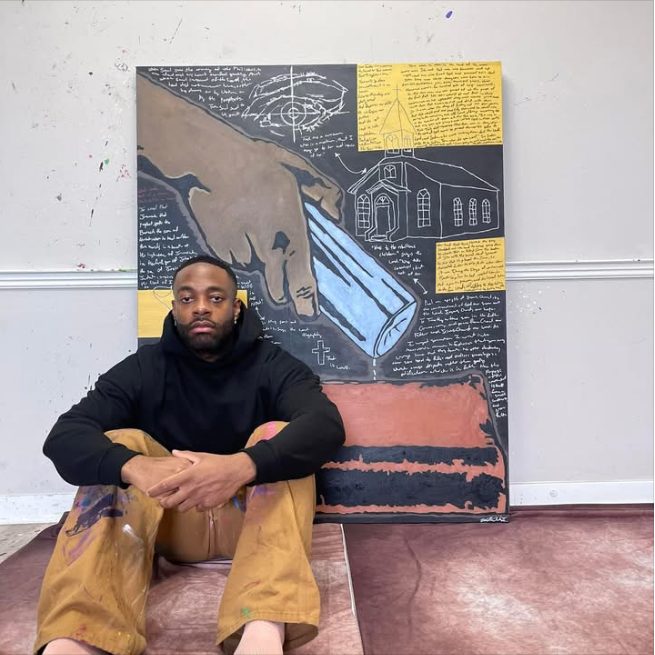 Willie Austin seated on the floor in front of Dirty Hand or Dirty Heart?, a painting of a hand pouring water from a bottle above a church and a money bag